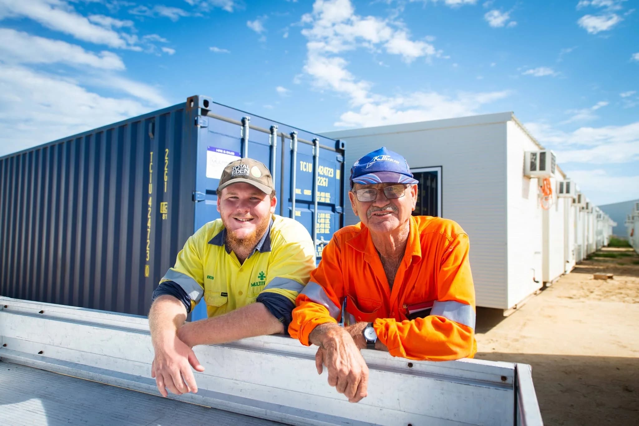 Two Multitrade team members smiling at the camera in the yard