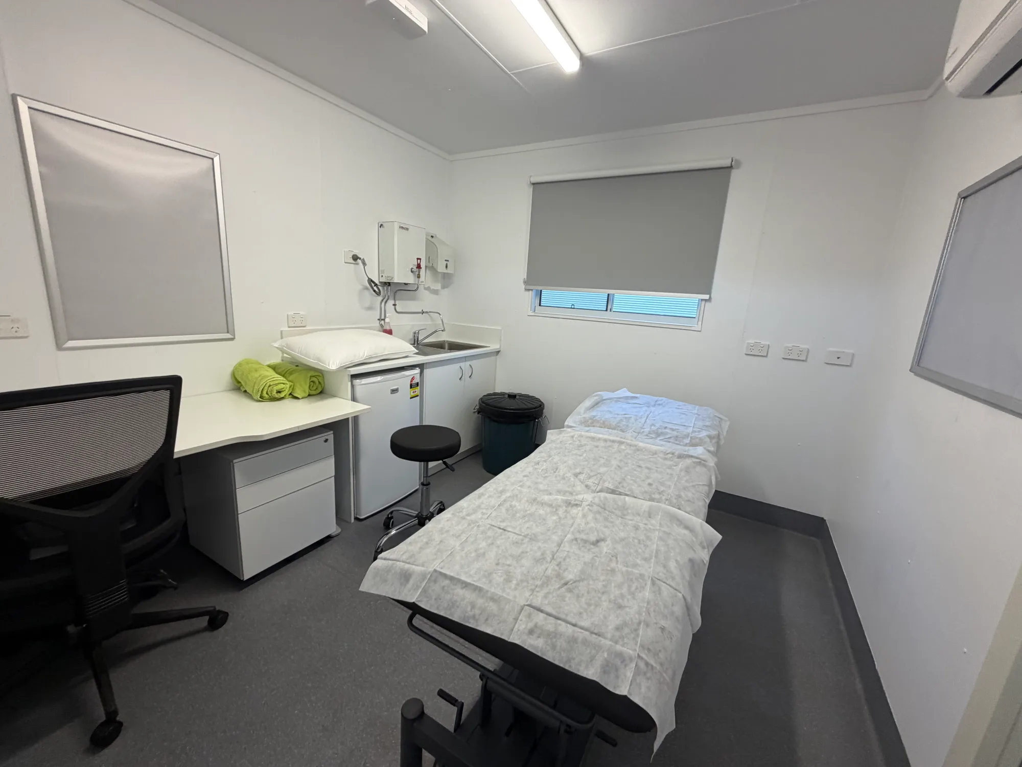 First-aid room with an examination couch, desk, sink and under-bench cabinetry