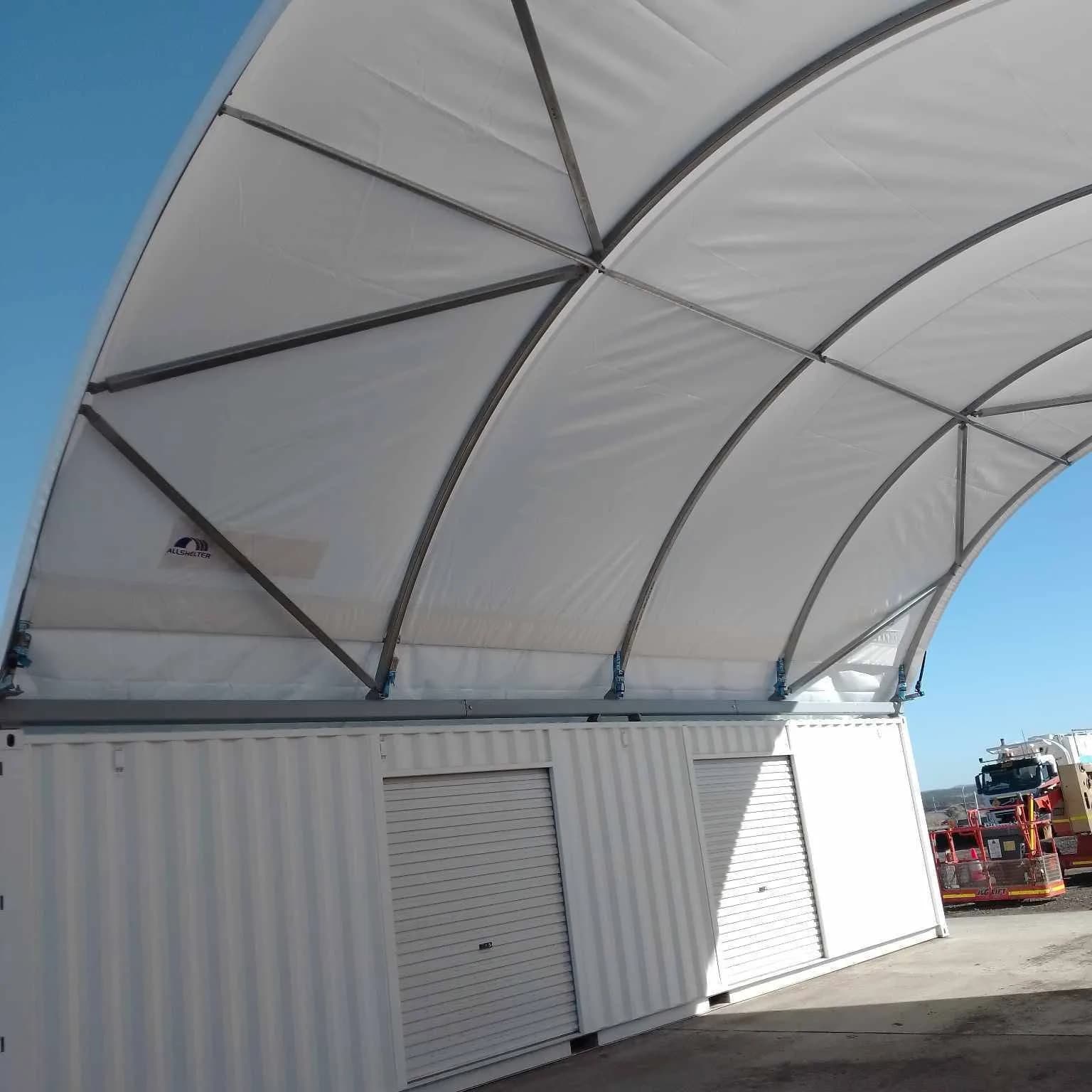Igloo shelter frame and fabric roof above shipping containers with roller doors