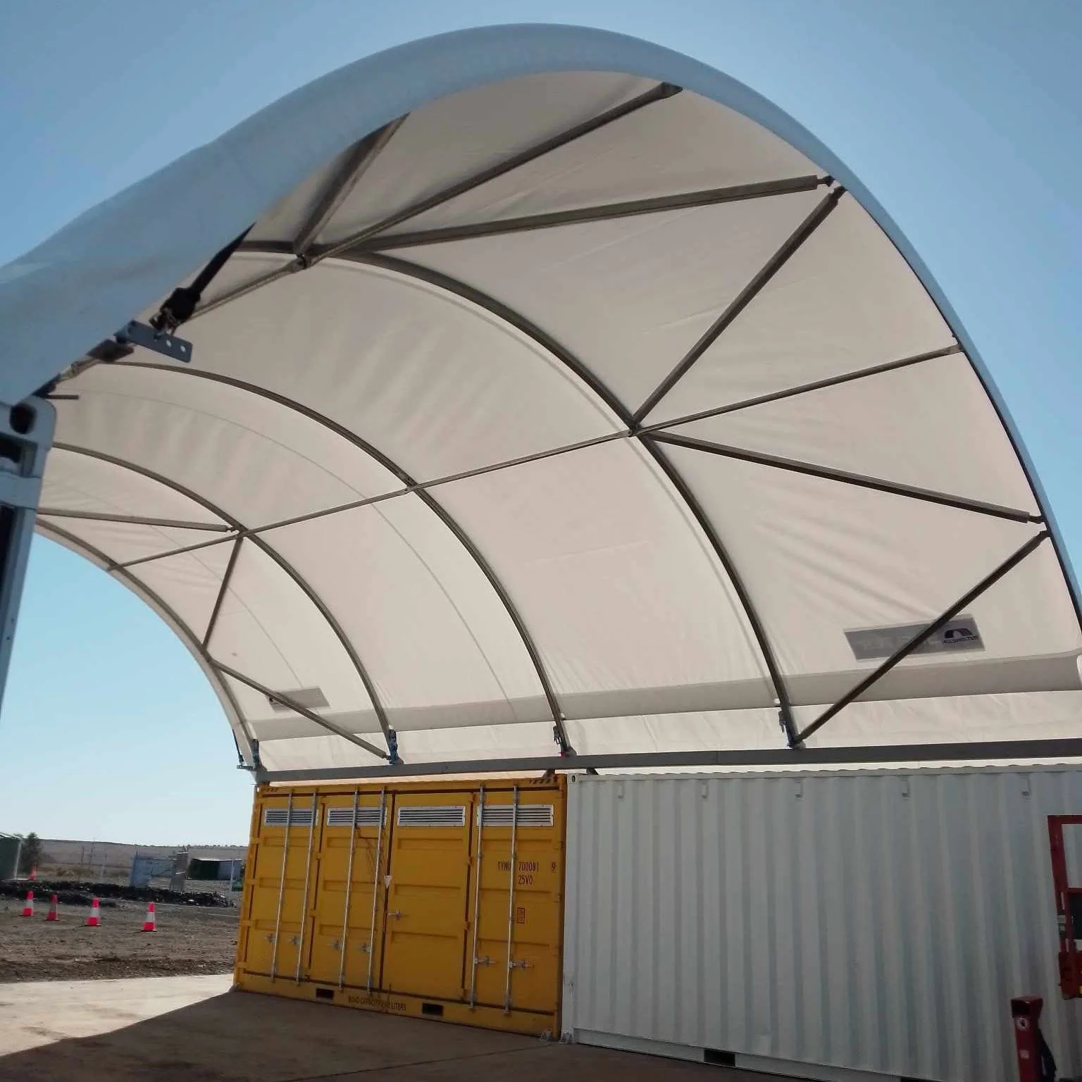 Curved shelter frame and bracing beneath a white fabric cover