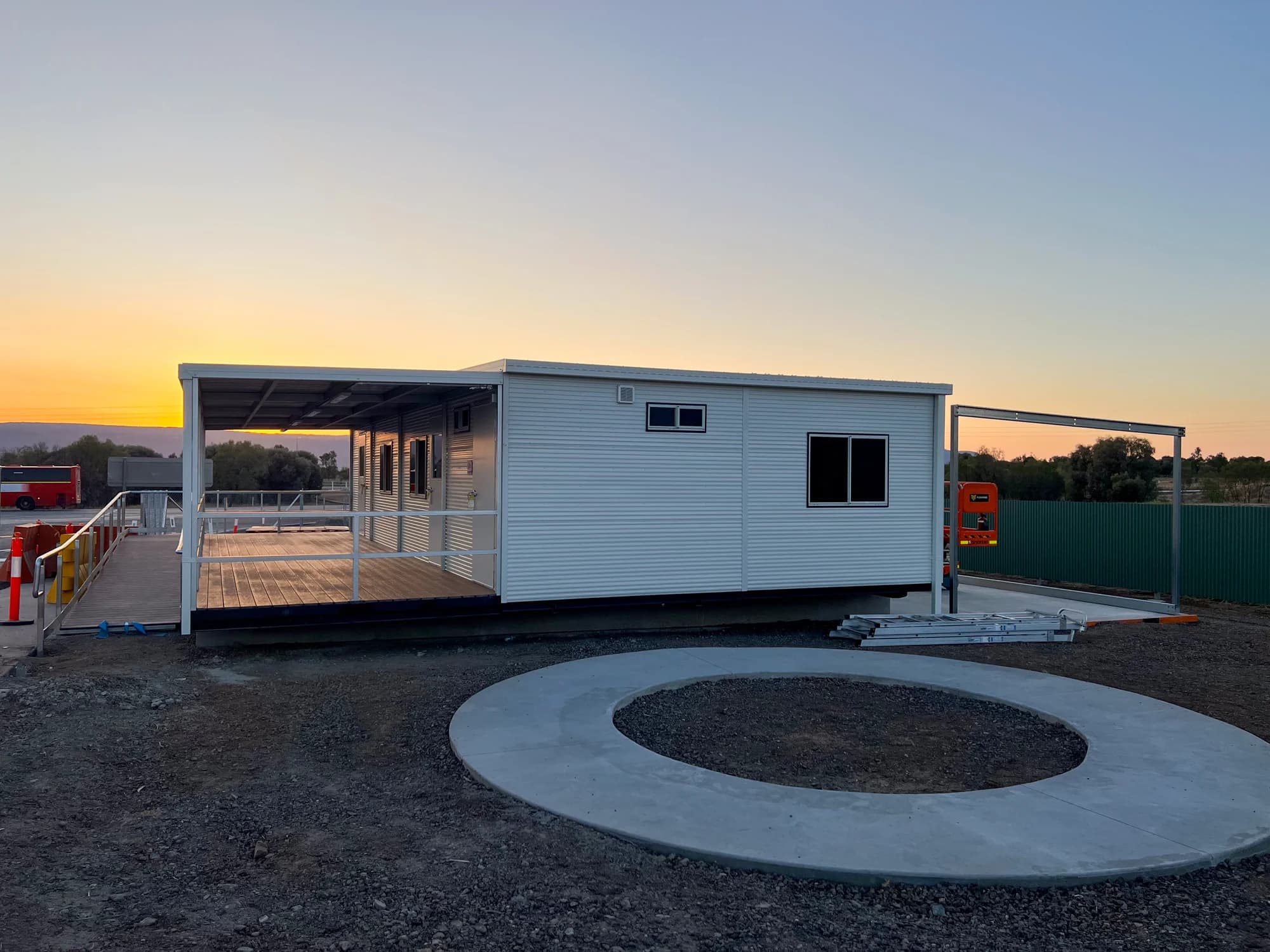 Installed building at sunset with its covered deck, access ramp and curved concrete path