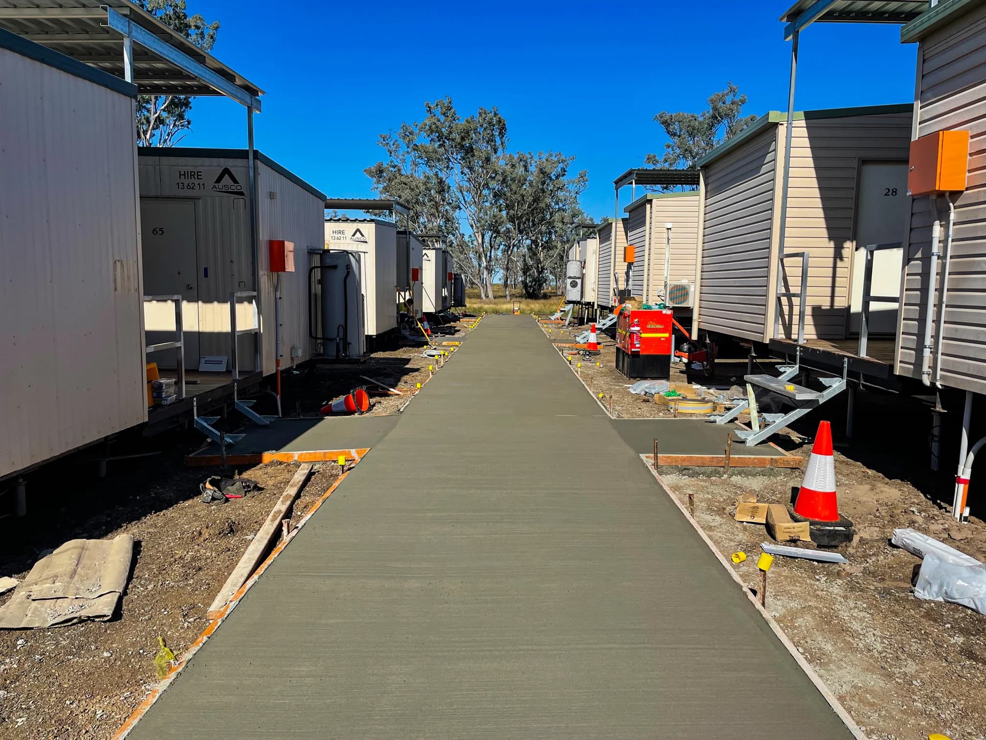 Finished concrete path running between two rows of site buildings