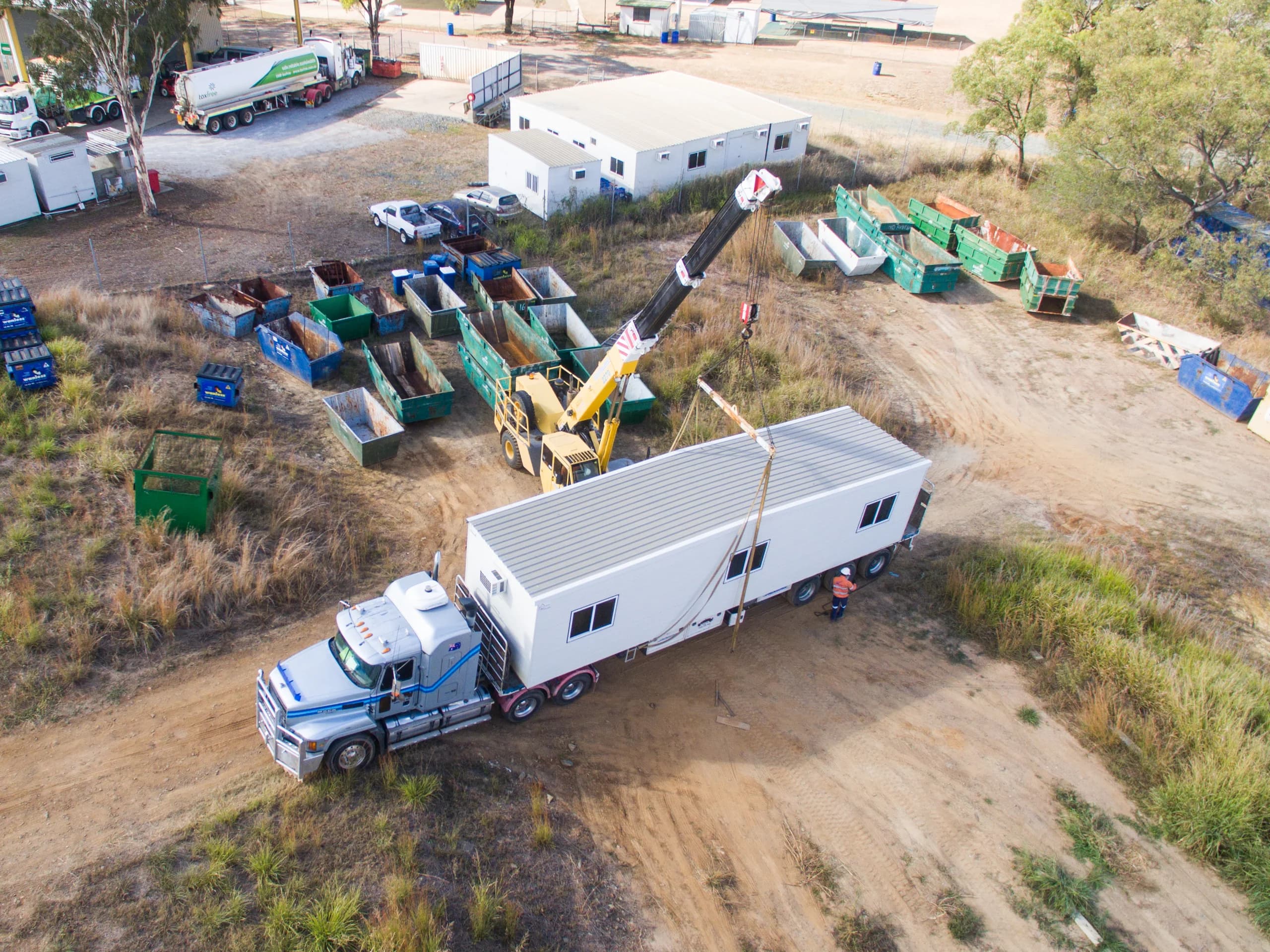 Aerial view of a crane and truck installing a transportable building on site