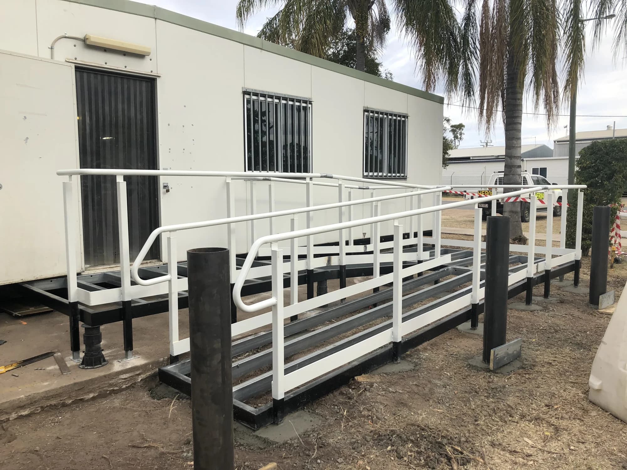 Side view of a ramp under construction, showing uncovered floor framing and handrails