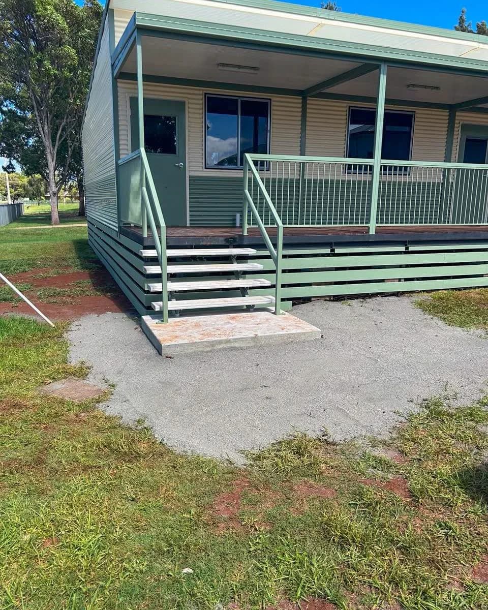 Stairs and green handrails connecting a concrete landing to the school complex veranda