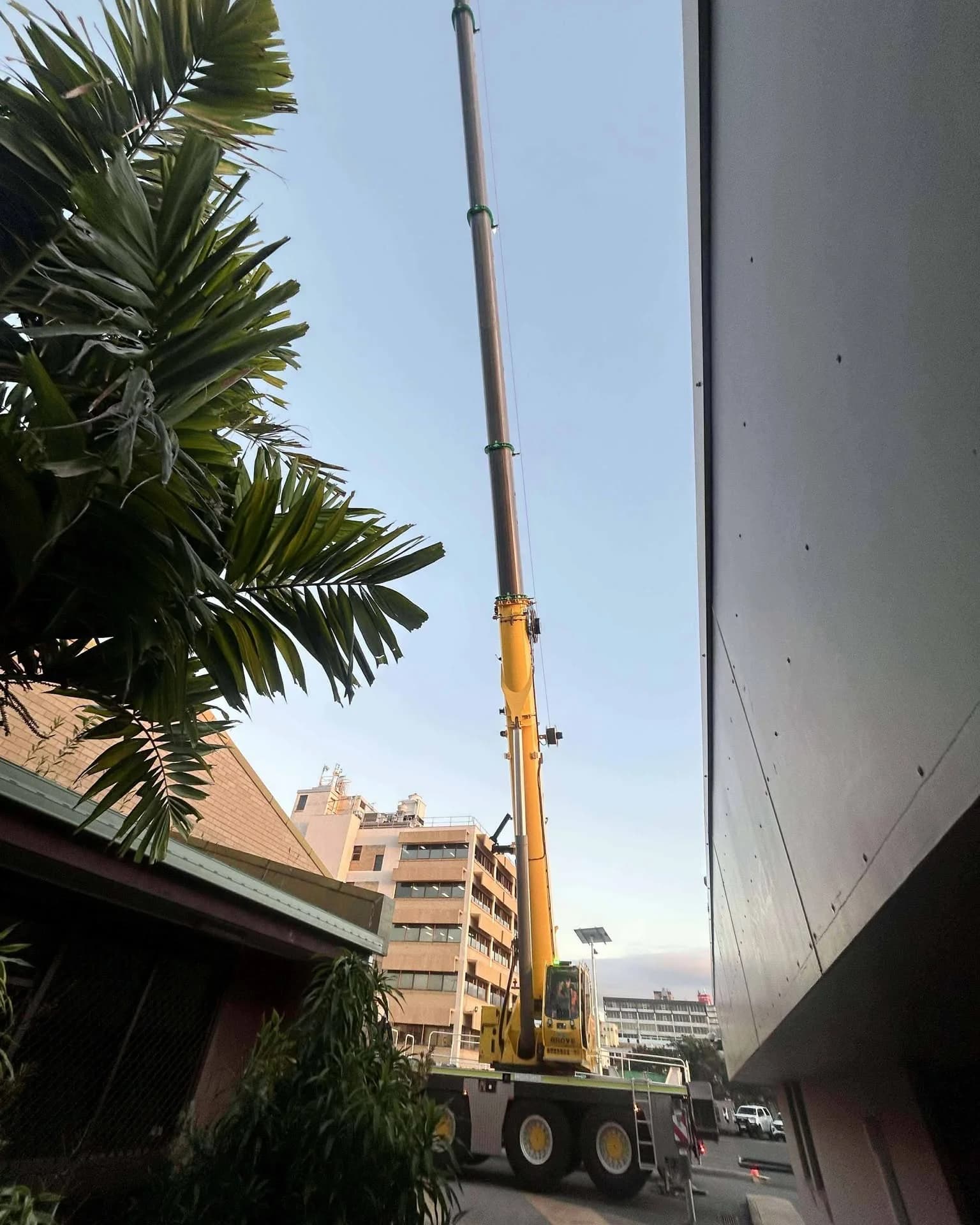 Mobile crane operating in a narrow space beside existing buildings and trees