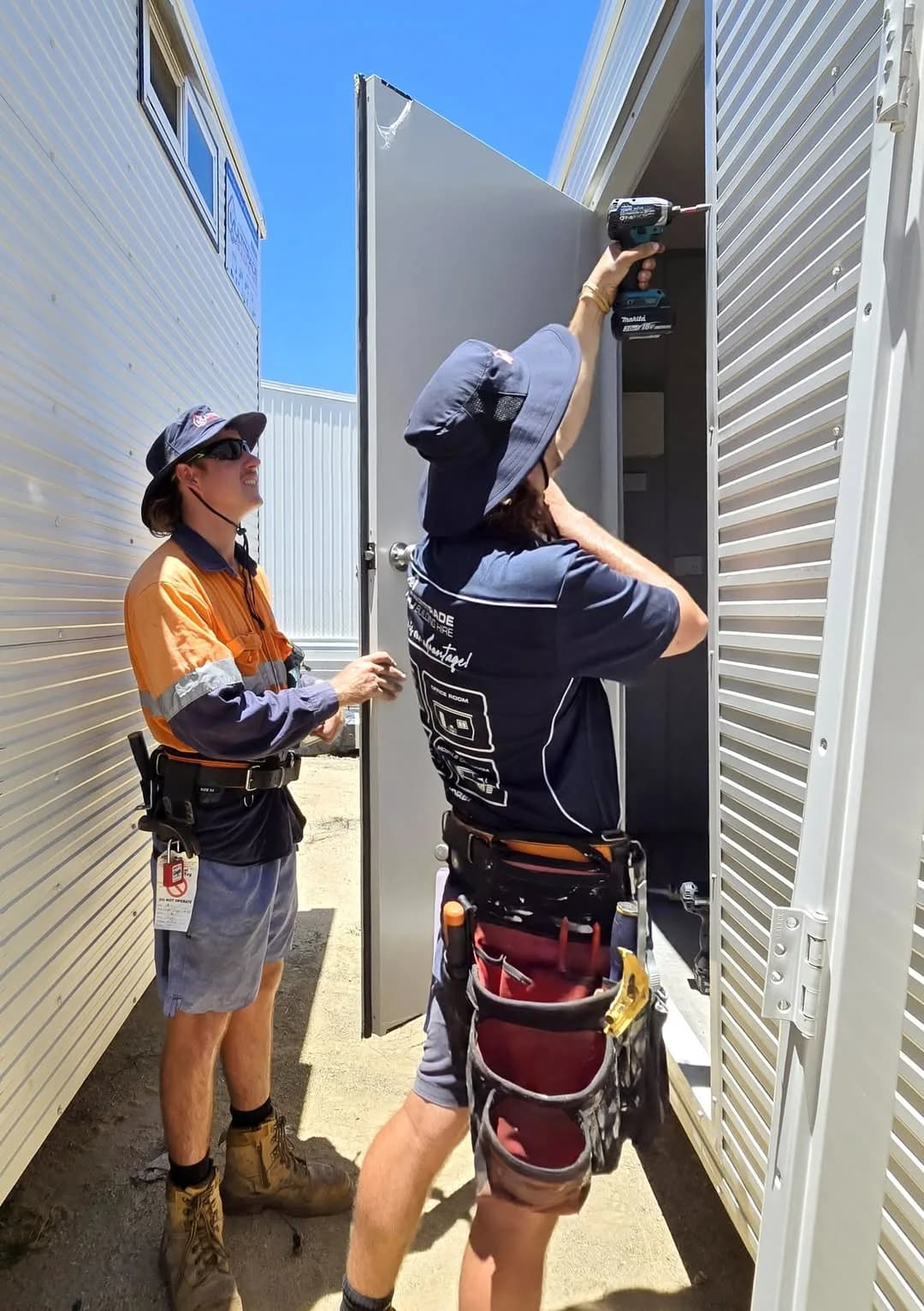 Multitrade team members working together on a portable building door