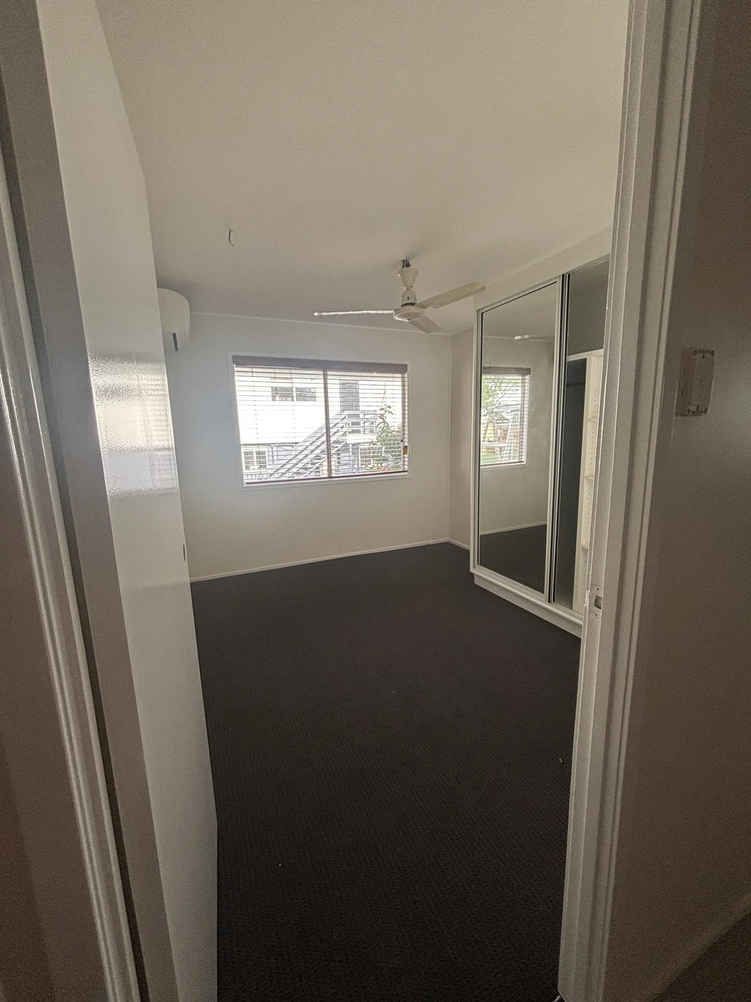 Bedroom during residential maintenance with carpet, a window and a mirrored built-in wardrobe