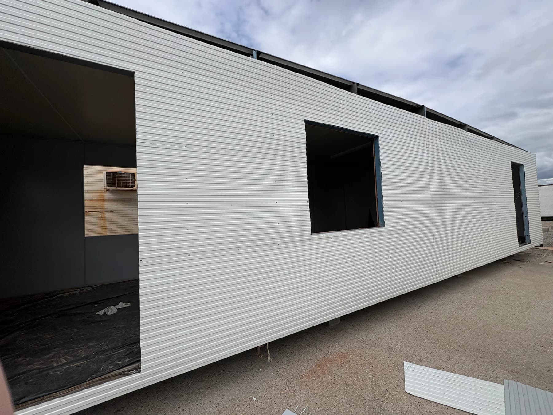 Portable building with new external cladding and unfinished window and door openings