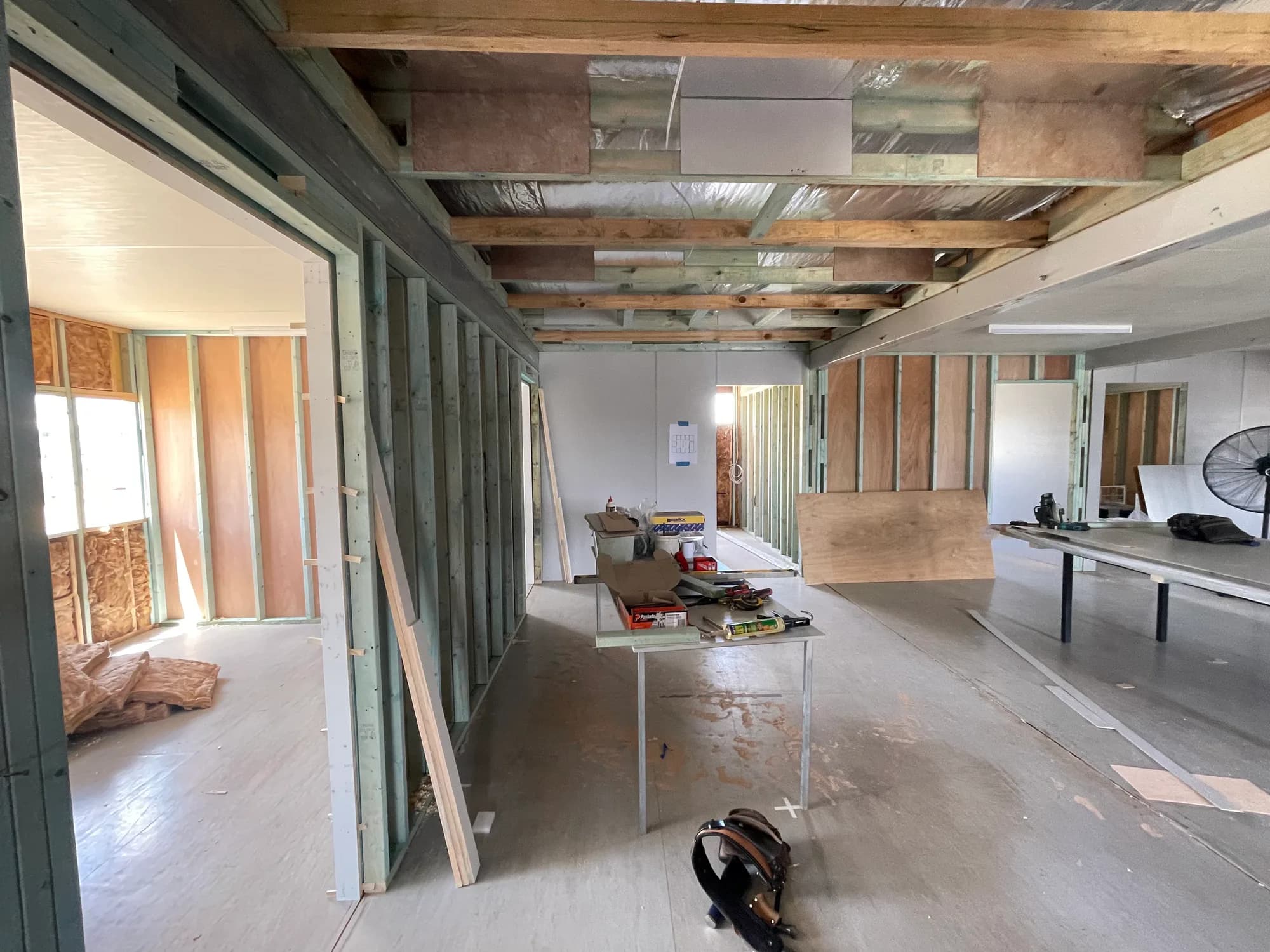Exposed ceiling timbers, insulation and wall studs beside partially lined rooms during complex repairs