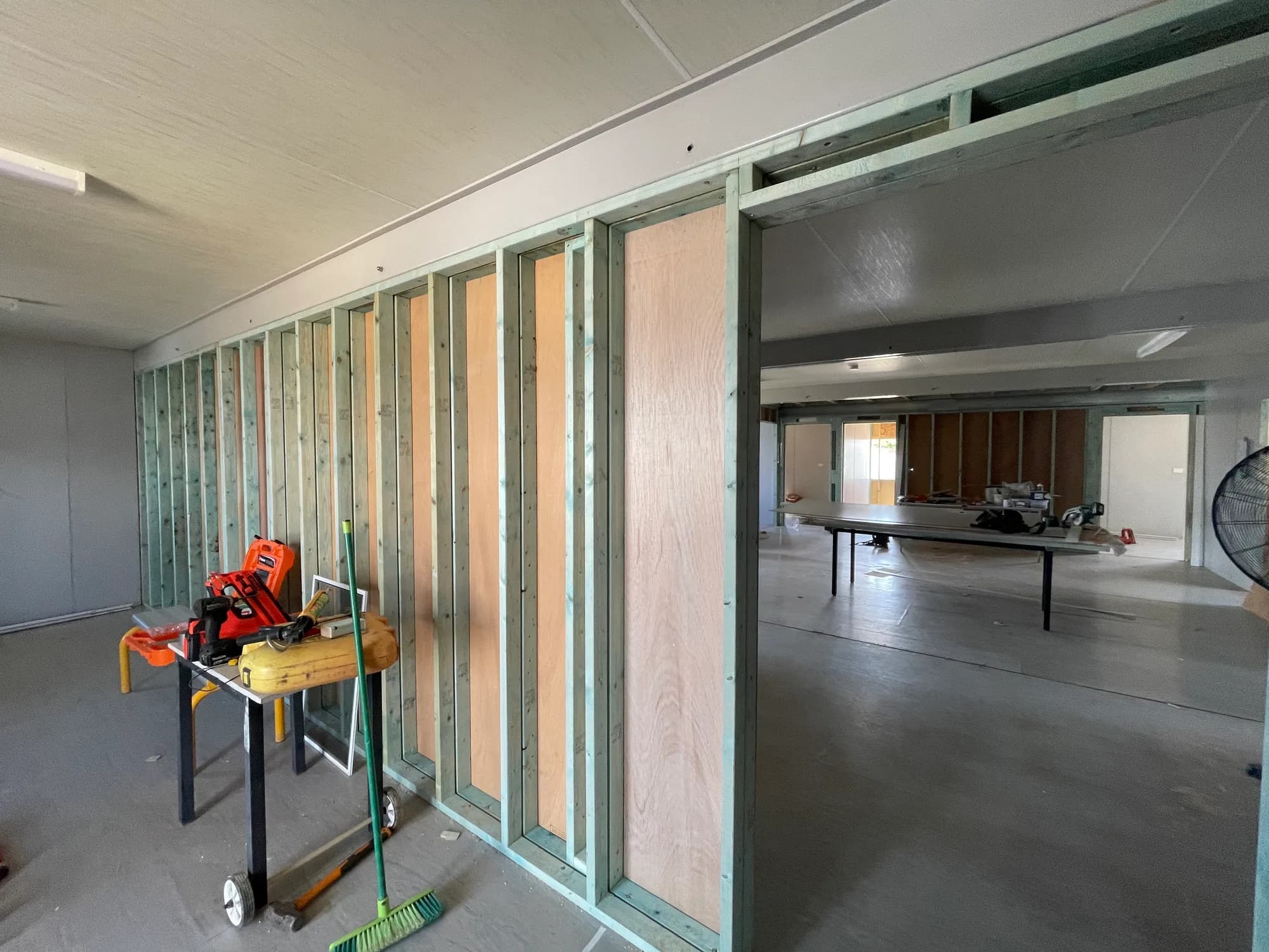 Exposed timber wall framing and a wide opening inside a building complex during interior repairs