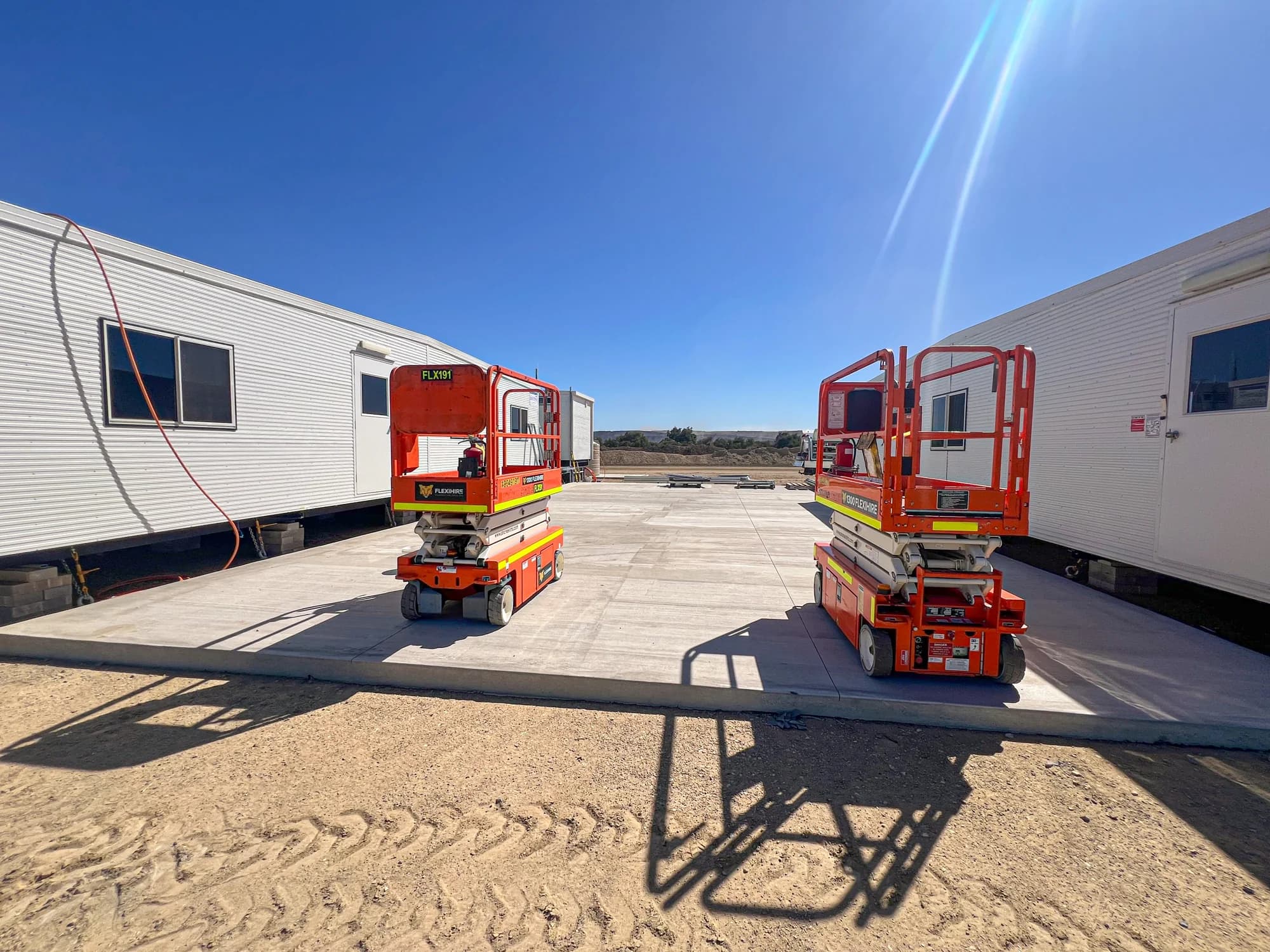 Fresh concrete between installed portable buildings with two scissor lifts during 3 North works