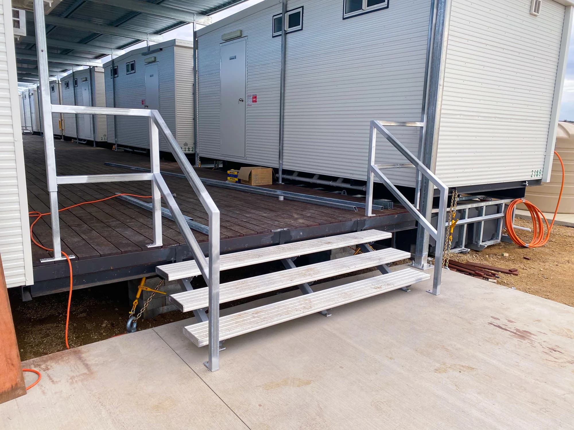 Steel stairs and handrails connecting a concrete path to the covered deck at Peak Downs 3 North