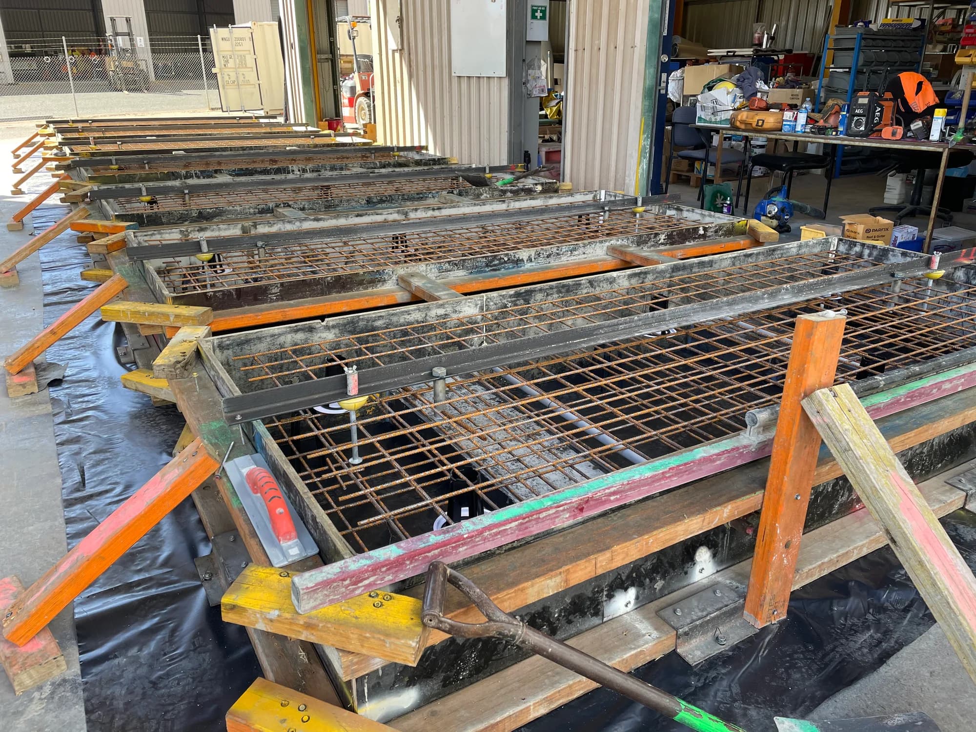 Rows of rectangular footing forms with reinforcement mesh and bracing in a workshop