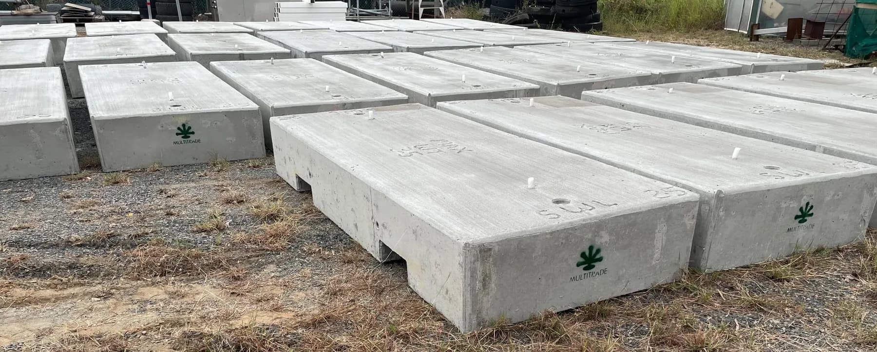 Rows of finished modular concrete tie-down blocks in the yard