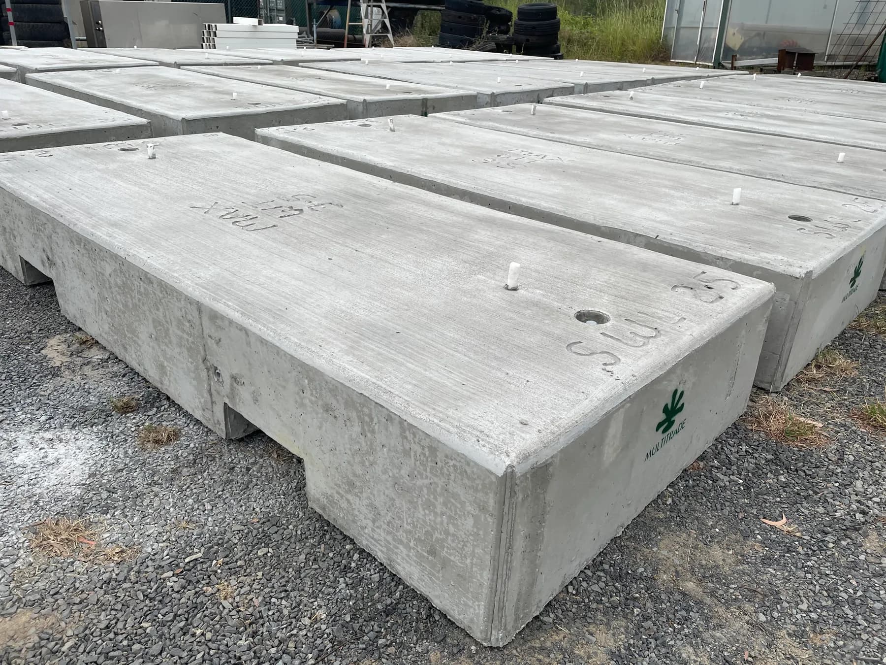 Finished rectangular precast concrete tie-down blocks with Multitrade markings arranged in the yard
