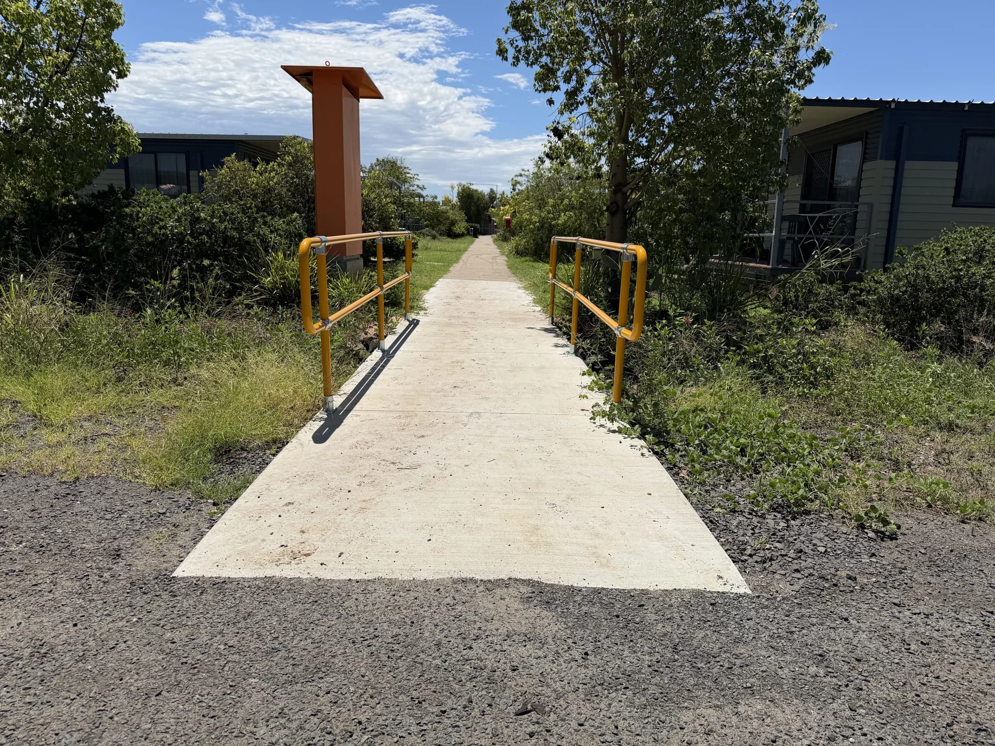 Concrete path and yellow handrails connecting to an existing walkway