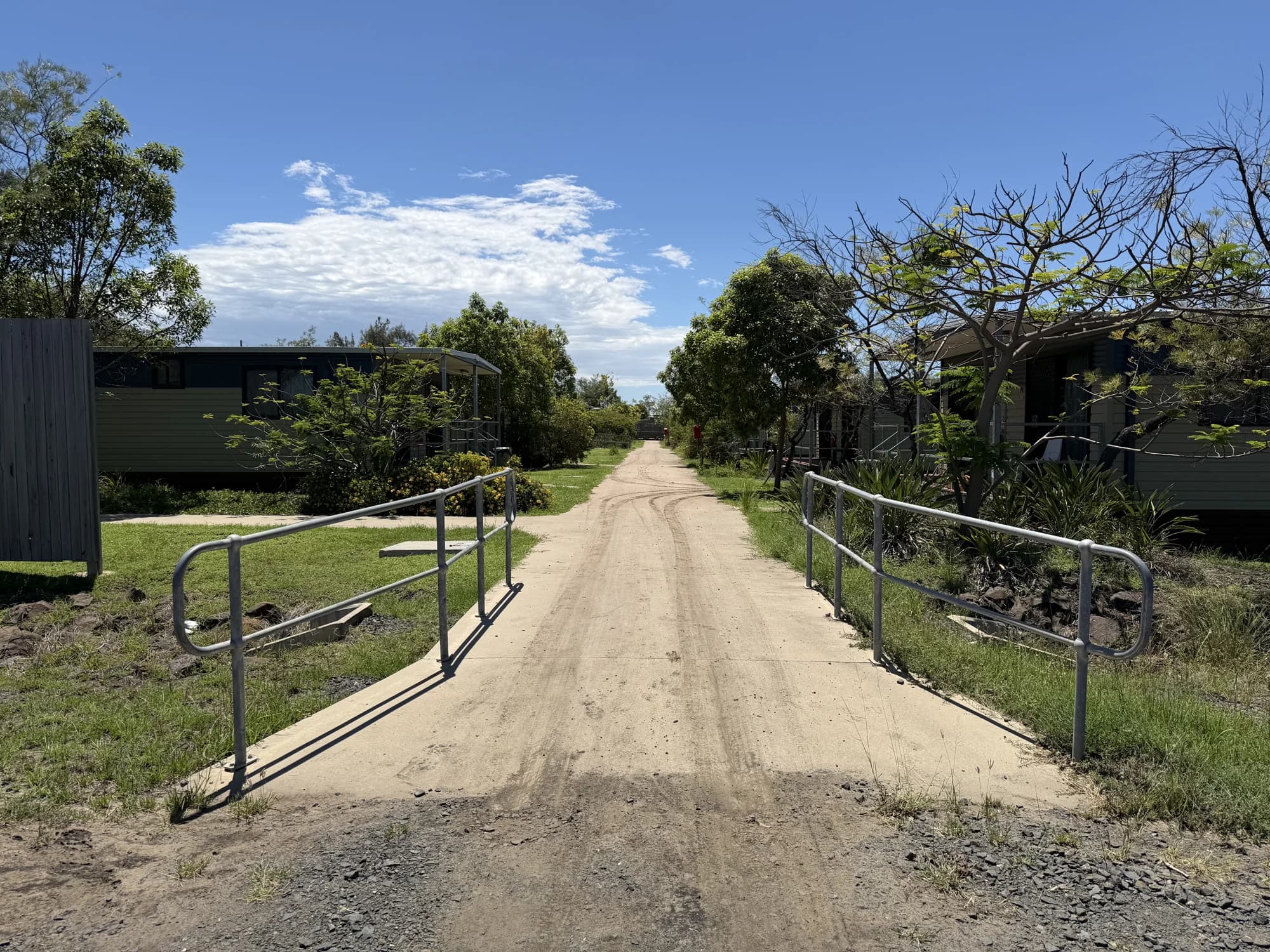 Wide concrete crossing with grey metal handrails and a visible drainage headwall