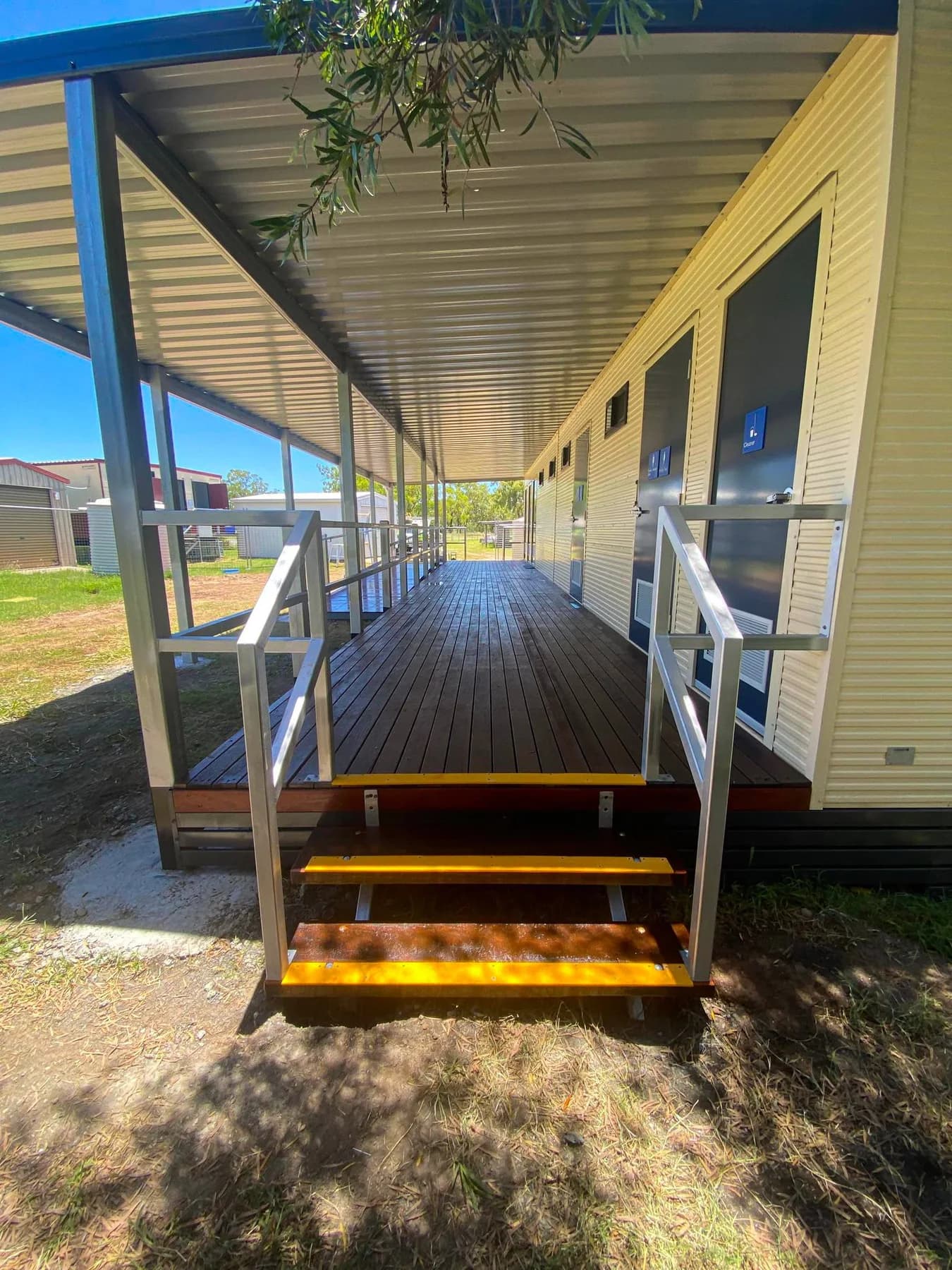 Timber stairs with yellow edge strips leading to a long covered deck