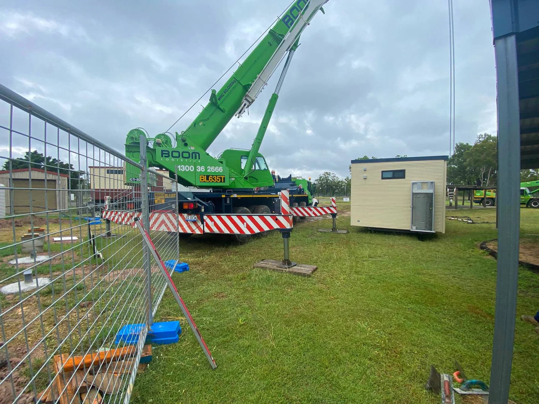 Mobile crane beside an ablution building inside a fenced installation area