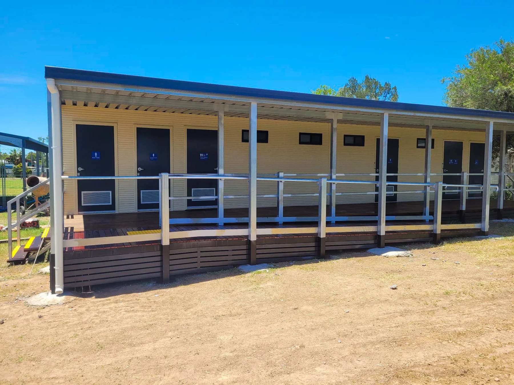 School amenities building with a covered timber deck, access ramp and metal handrails