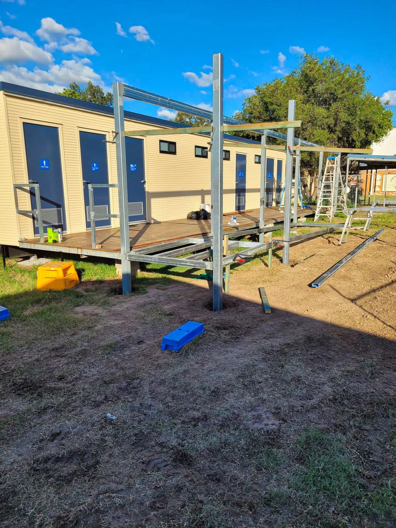 Exposed steel posts and beams beside the ablution building during deck and roof construction