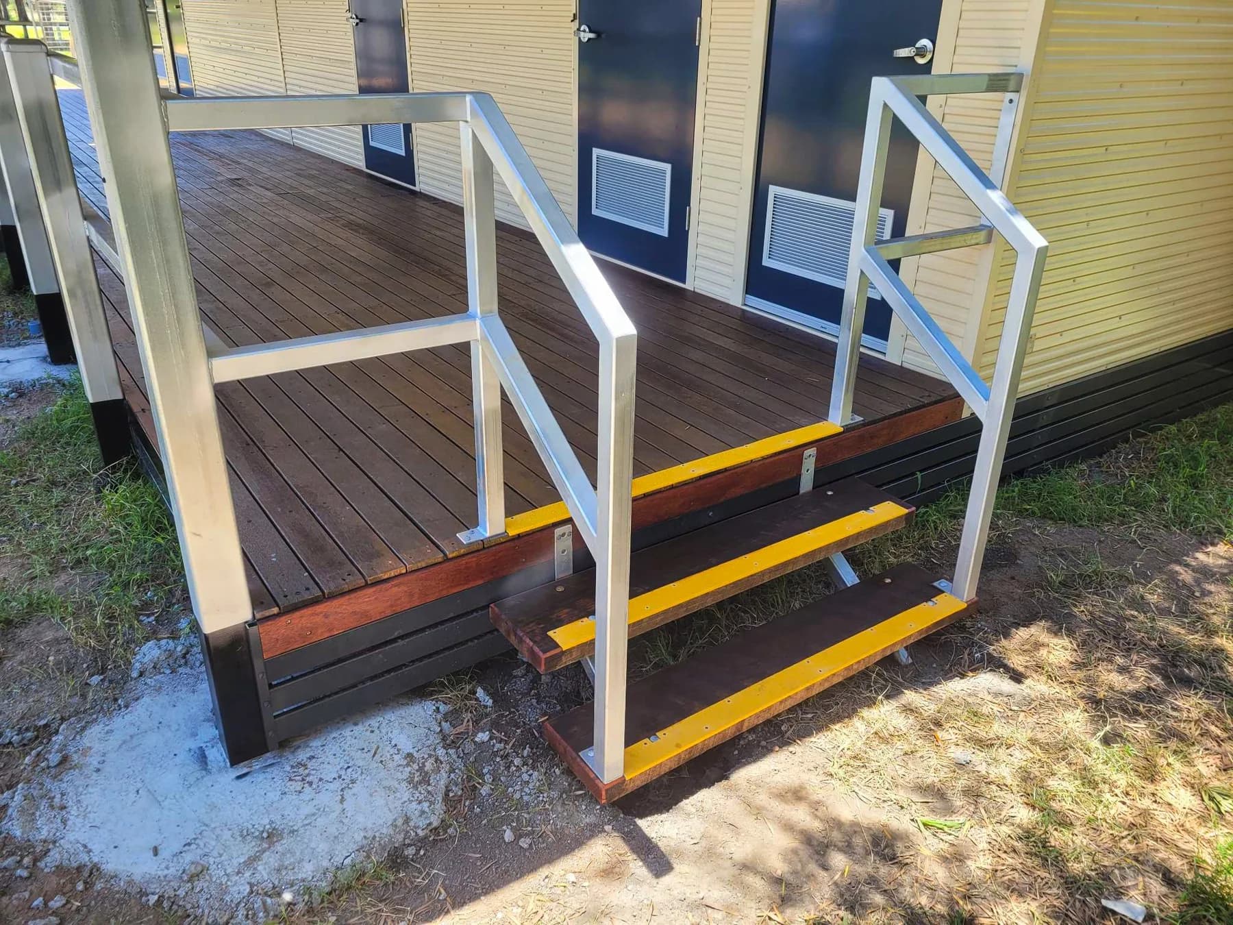 Close view of timber steps with yellow edge strips and metal handrails