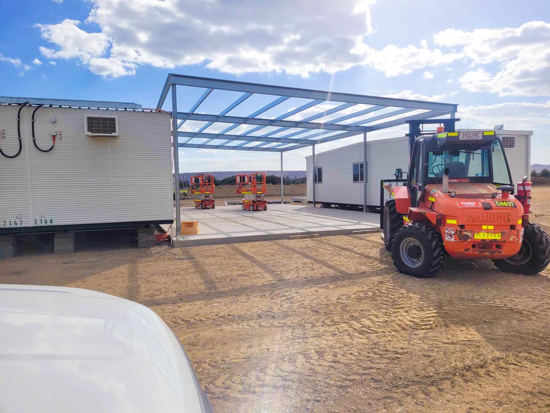 Steel canopy framing beside portable buildings during site construction